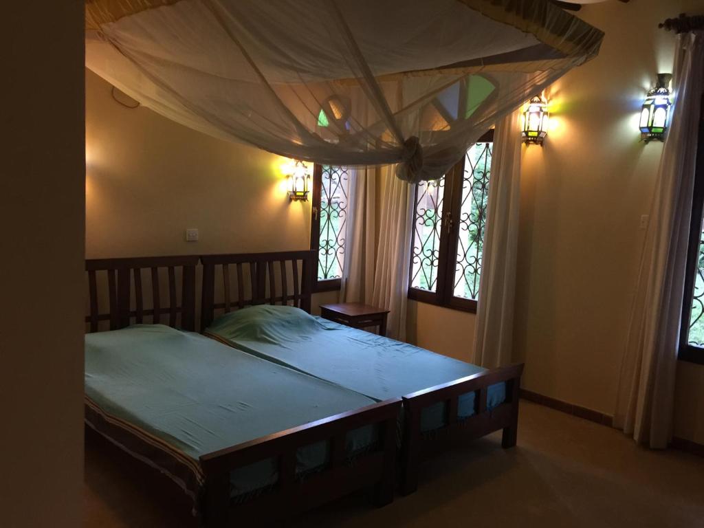 - une chambre avec un lit à baldaquin et 2 fenêtres dans l'établissement Marula Park, à Diani Beach