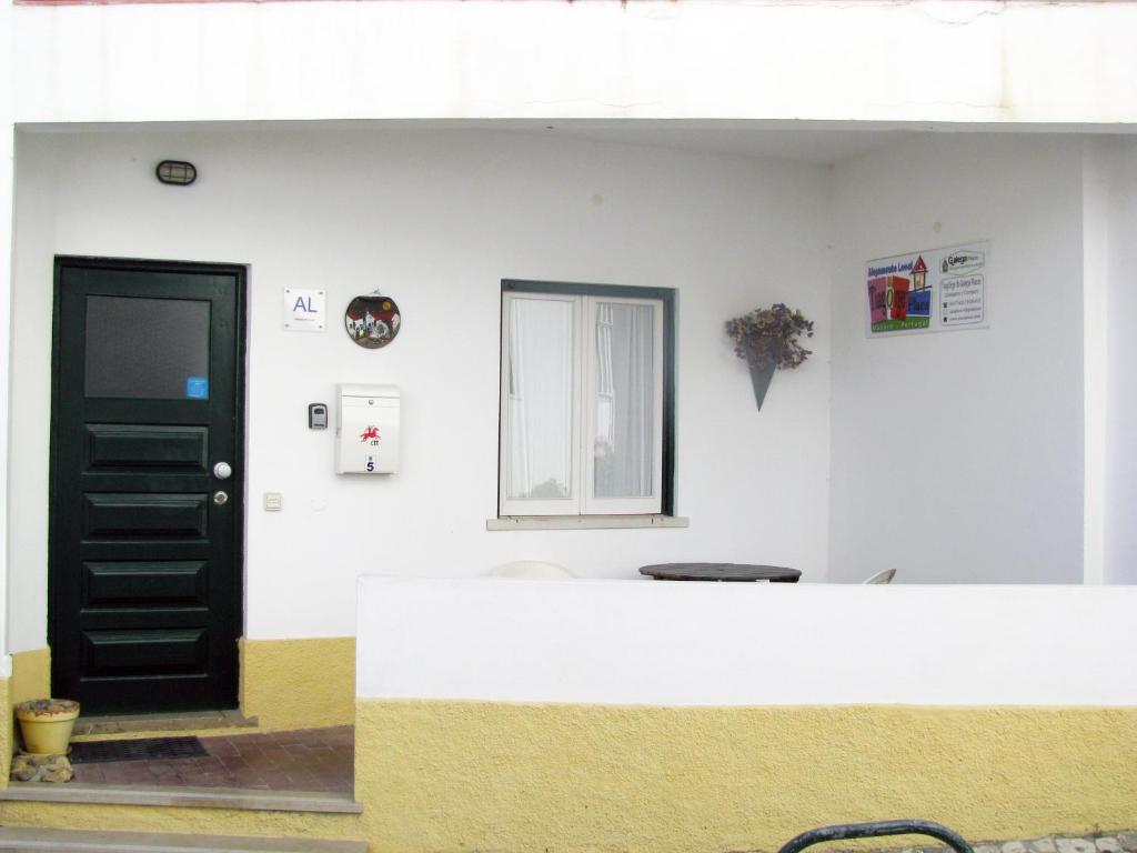 een witte muur met een zwarte deur en een raam bij Alojamento Tiago & Jorge Guesthouse in Nazaré