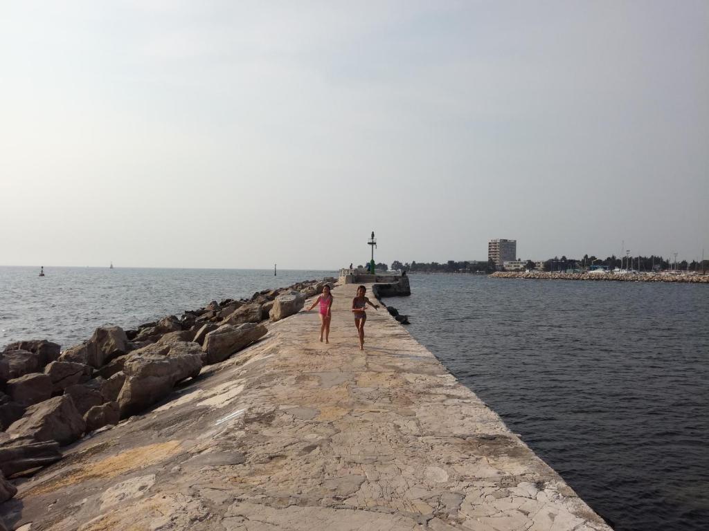 twee mensen lopen op een pier bij het water bij Guest House Kvartin in Umag