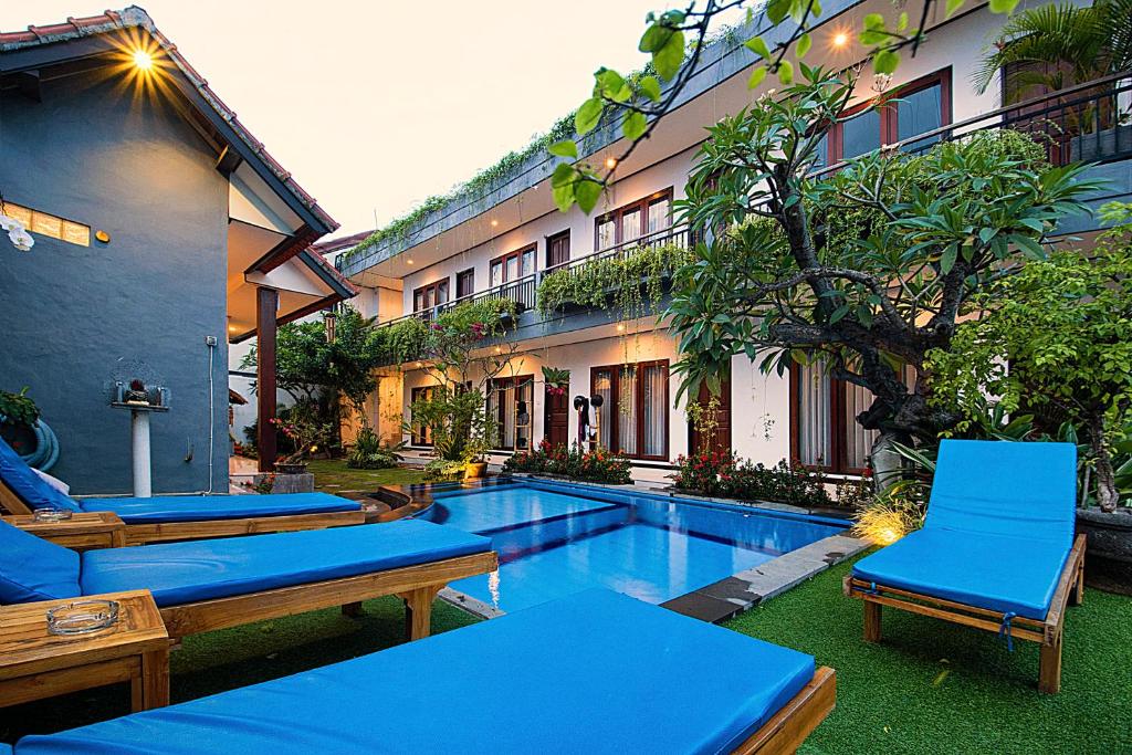 un complejo con piscina, sillas y un edificio en Bali Full Moon Guest House, en Canggu