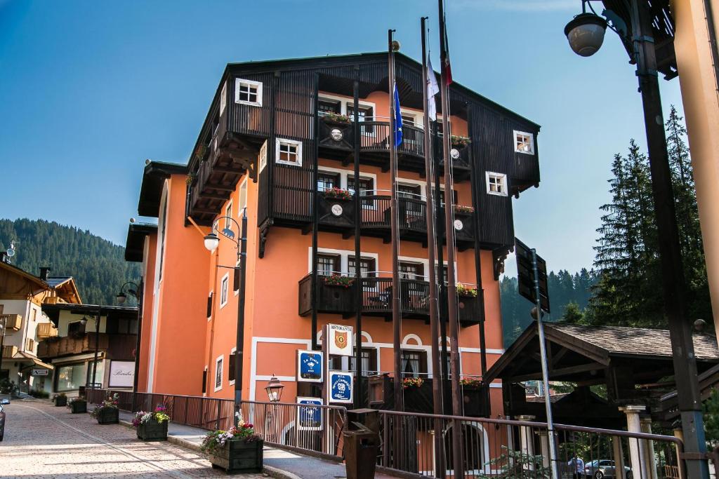 un edificio alto de color naranja con balcones en una calle en Hotel Posta R.T.A., en Madonna di Campiglio