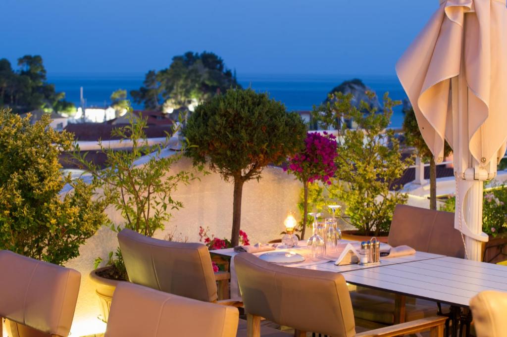 un tavolo con sedie e un ombrellone su un patio di Olympic Hotel a Párga