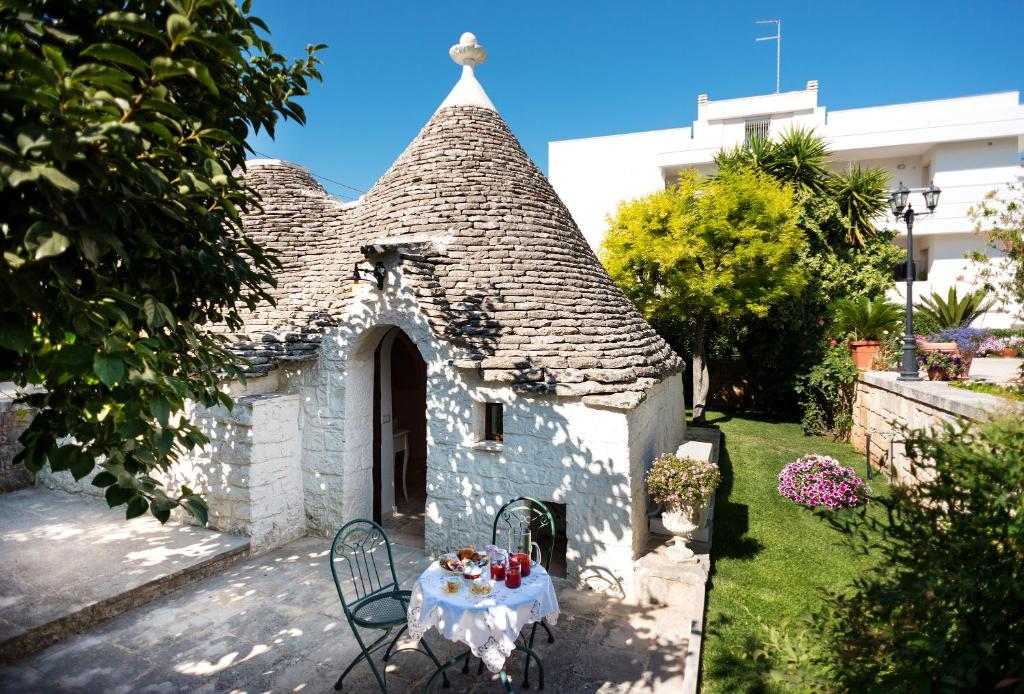 uma pequena casa com uma mesa em frente em Trullo Giardino Fiorito em Alberobello