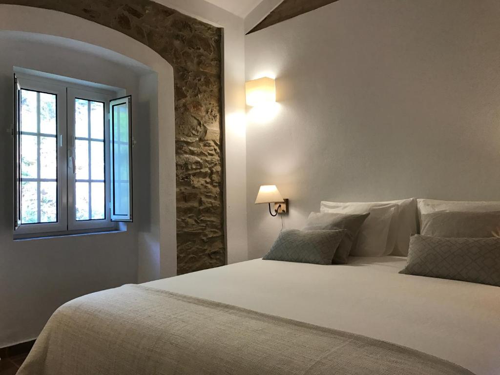 1 dormitorio con 1 cama blanca grande y ventana en Azeite de Marvão, Olivoturismo casa Mestre do Lagar, en Marvão