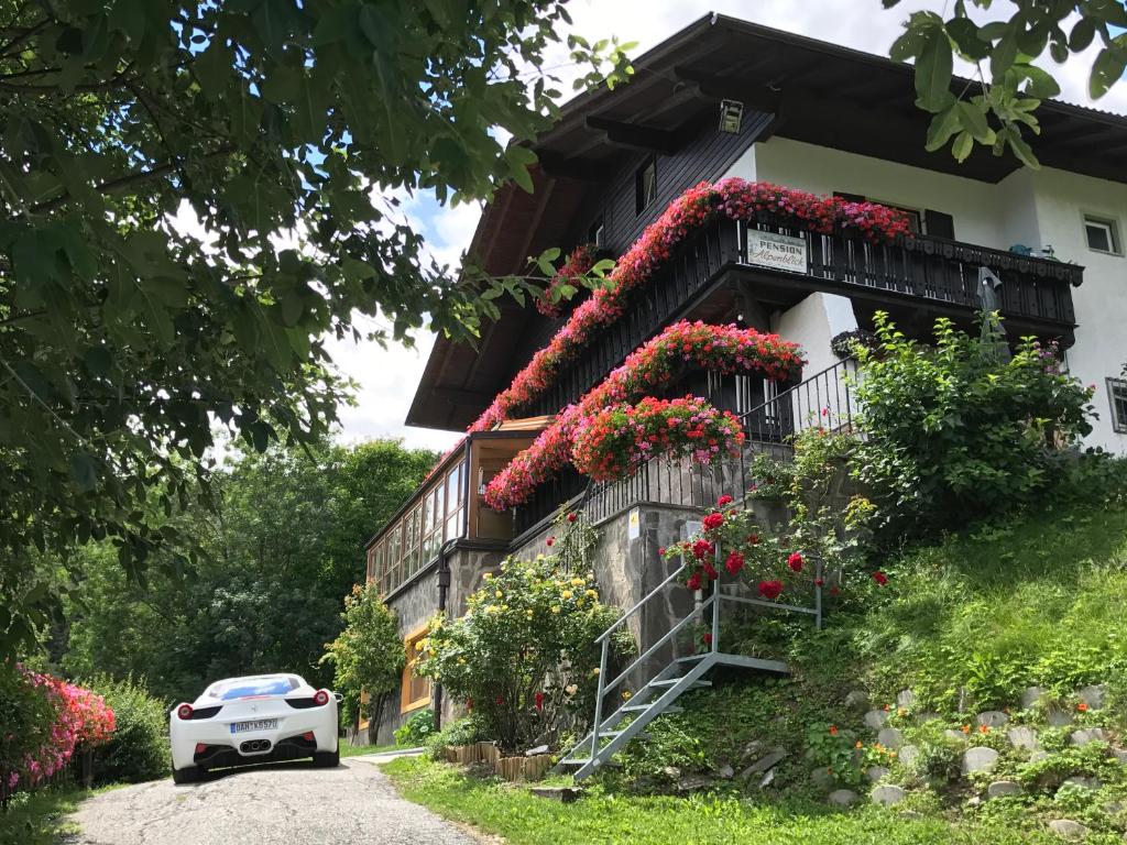 um carro branco estacionado em frente a uma casa com flores em Alpenblick Bed & Breakfast em Vipiteno