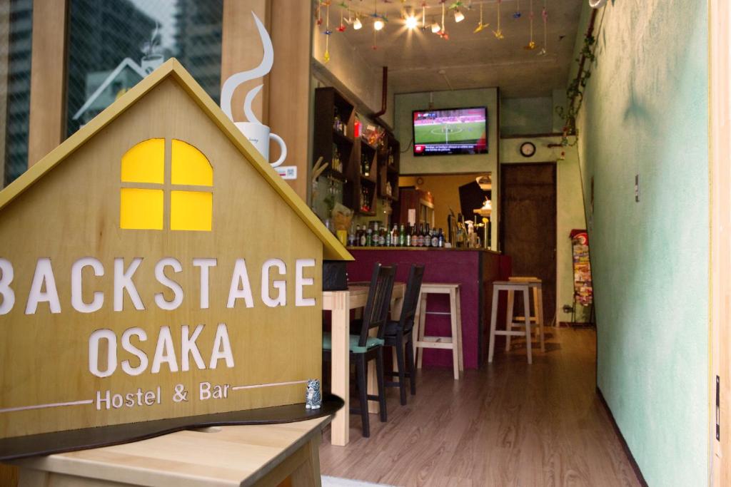 un restaurante con un cartel que dice detrás del escenario osaka en Backstage Party Hostel & Bar, en Osaka