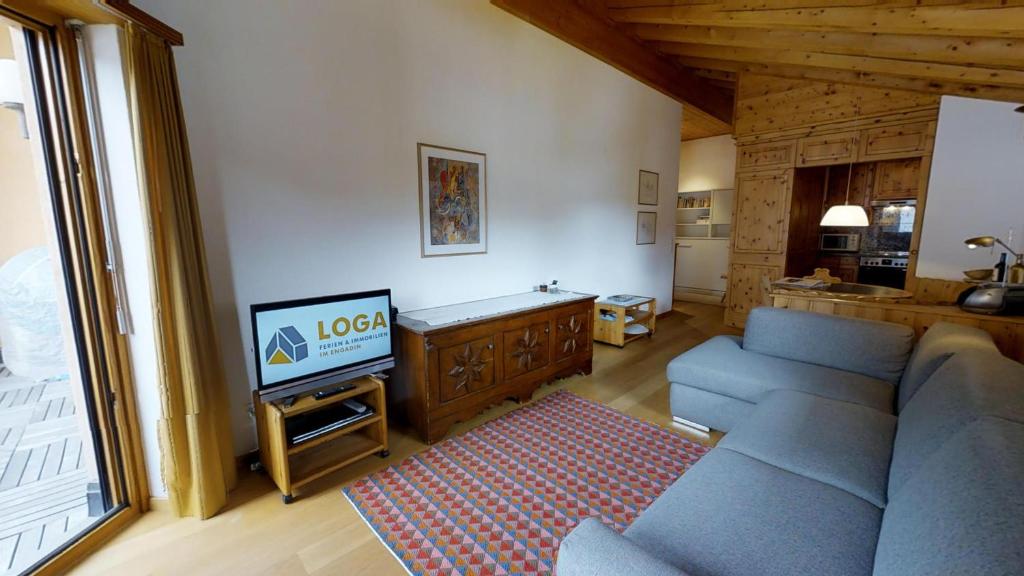 a living room with a blue couch and a television at Carla 12 in Sils Maria