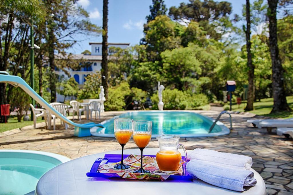 two glasses of orange juice on a table next to a swimming pool at Hotel Gramado Palace in Gramado