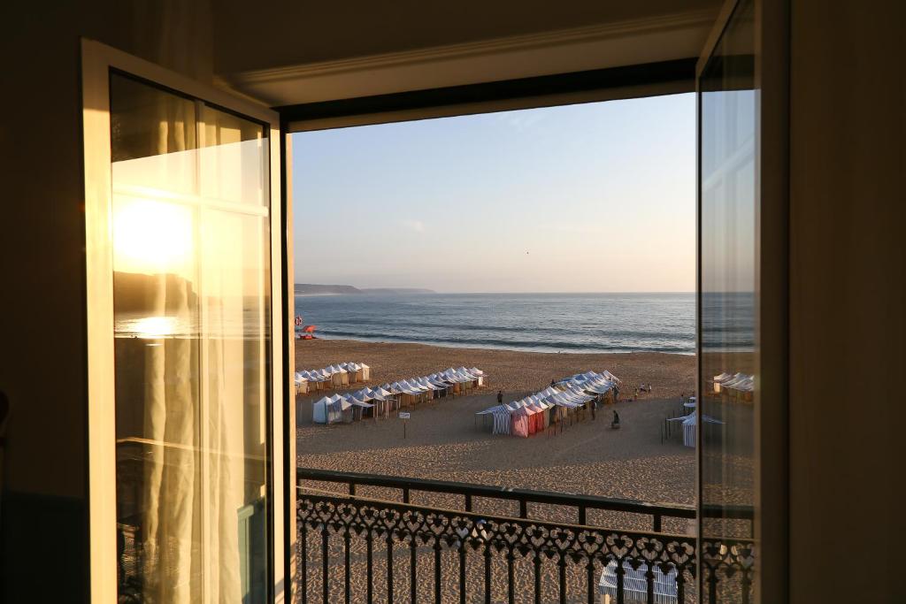 uma vista para a praia a partir de um quarto com uma janela em Feel Nazaré - Ocean View na Nazaré