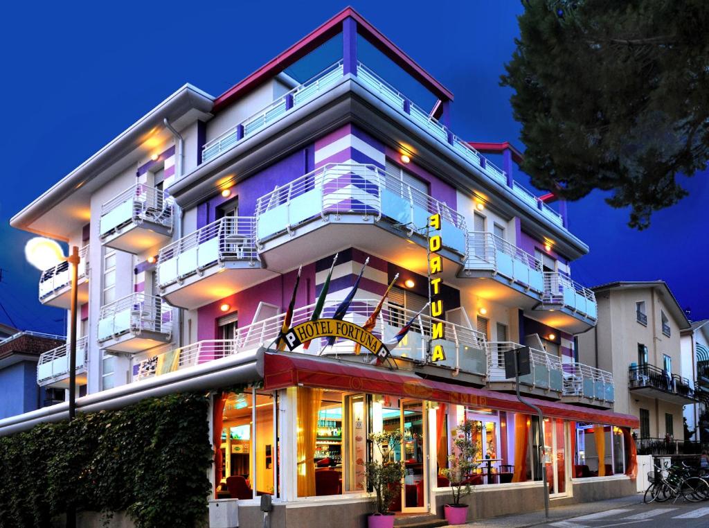 un edificio blanco alto con un restaurante frente a él en Hotel Fortuna, en Caorle