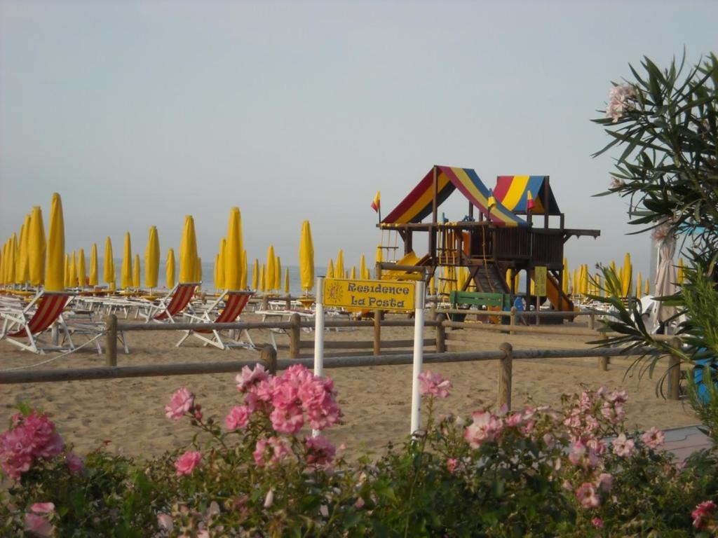 a beach with a playground and chairs and umbrellas at B&C Apartments in Lido di Jesolo