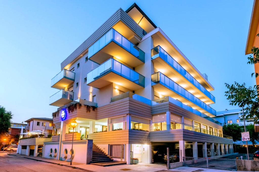 een hoog wit gebouw met blauwe balkons in een straat bij Hotel Mayer in Bibione