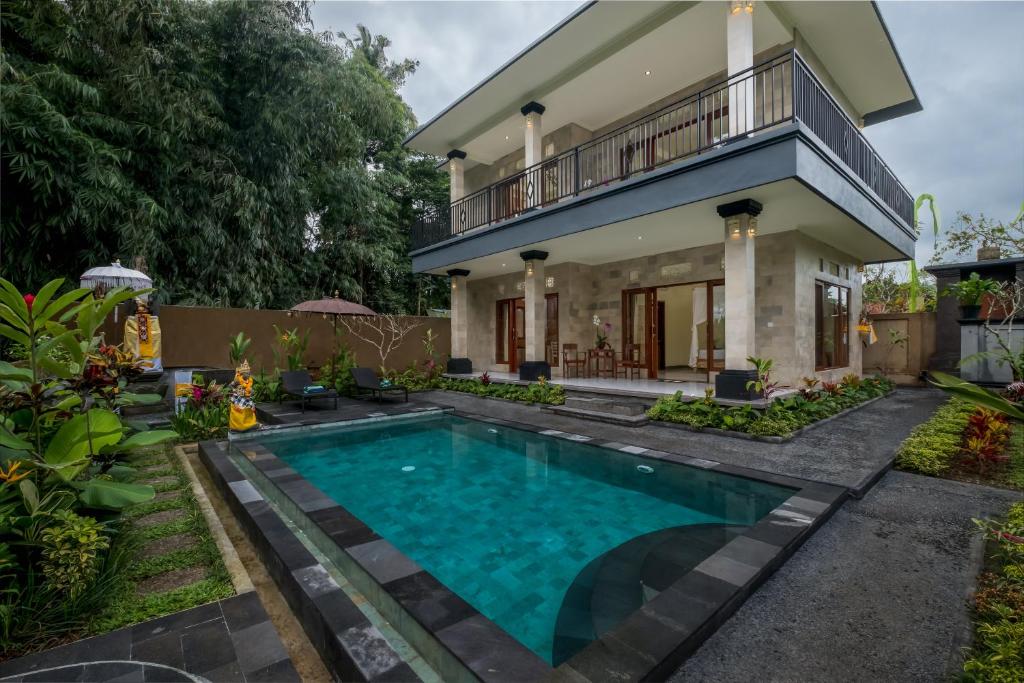 a house with a swimming pool in front of a house at Puri Astina Villa in Ubud