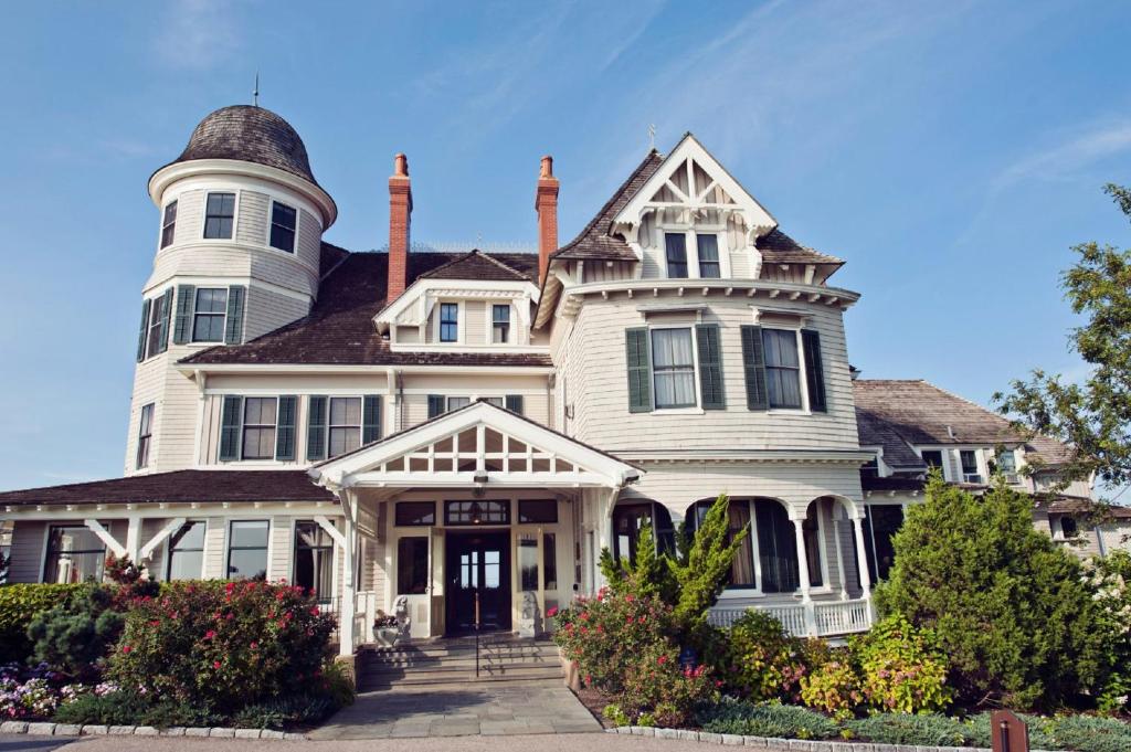 Une grande maison blanche avec une tourelle en haut dans l'établissement Castle Hill Inn, à Newport