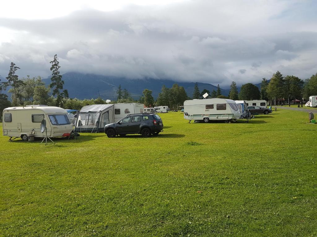 eine Gruppe von Zelten und Fahrzeugen, die auf einem Feld geparkt sind in der Unterkunft Camping Intercamp Tatranec in Tatranská Lomnica