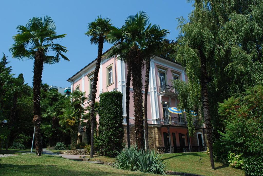 a building with palm trees in front of it at Hotel&Hostel Montarina in Lugano