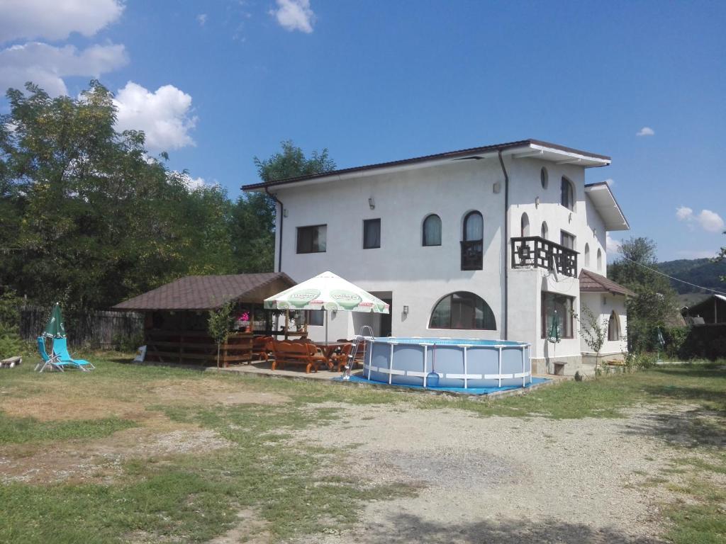 een groot wit huis met stoelen en tafels ervoor bij Vila Madudu in Vălenii de Munte