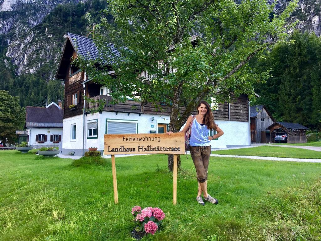 uma mulher ao lado de um cartaz no quintal em Landhaus Hallstättersee em Bad Goisern