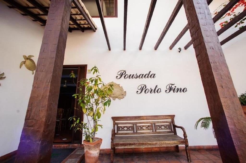 un panneau sur le mur d'un bâtiment avec un banc dans l'établissement Pousada Porto Fino, à Cabo Frio