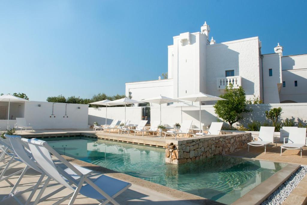 una piscina con sillas y un edificio en Masseria Le Torri, en Polignano a Mare