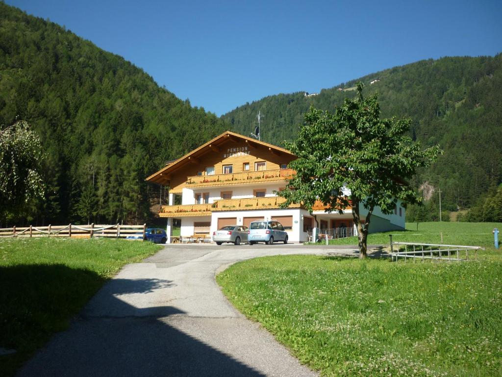 un grande edificio con macchine parcheggiate di fronte di Pension Wiesenhof a Campo di Trens