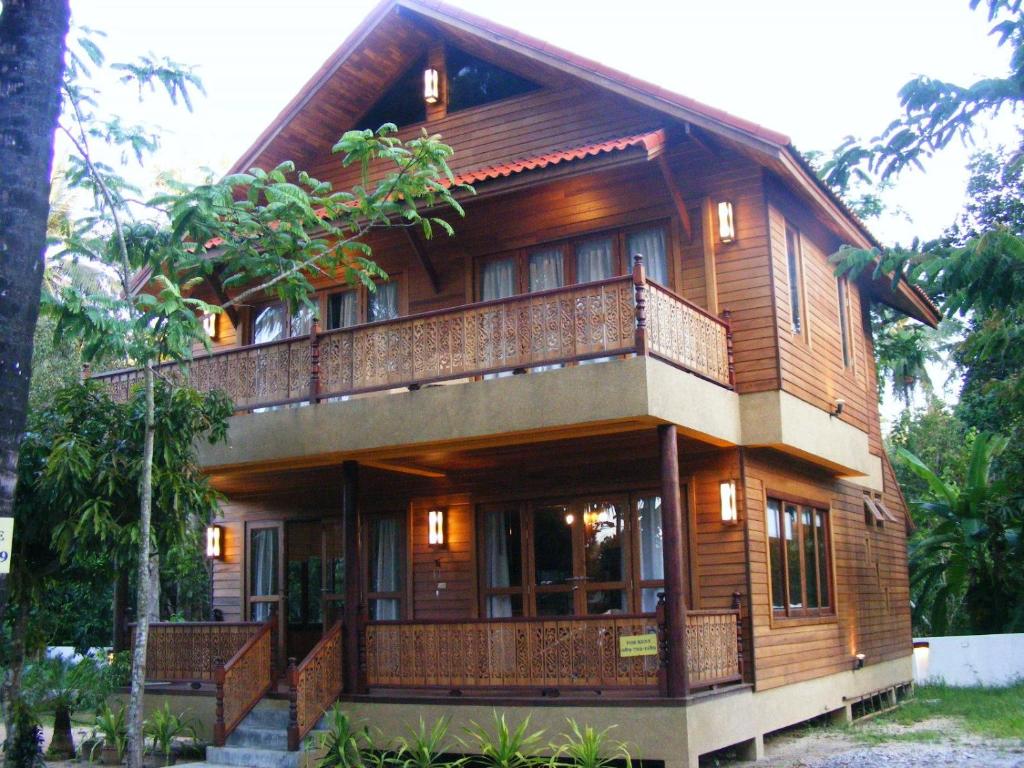 a wooden house with a balcony on top of it at Baan Nana Villa in Mae Nam