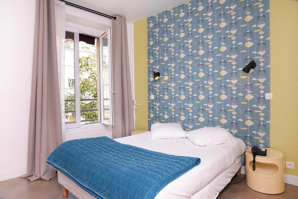 1 dormitorio con 1 cama con pared azul en Zazie Hôtel, en París