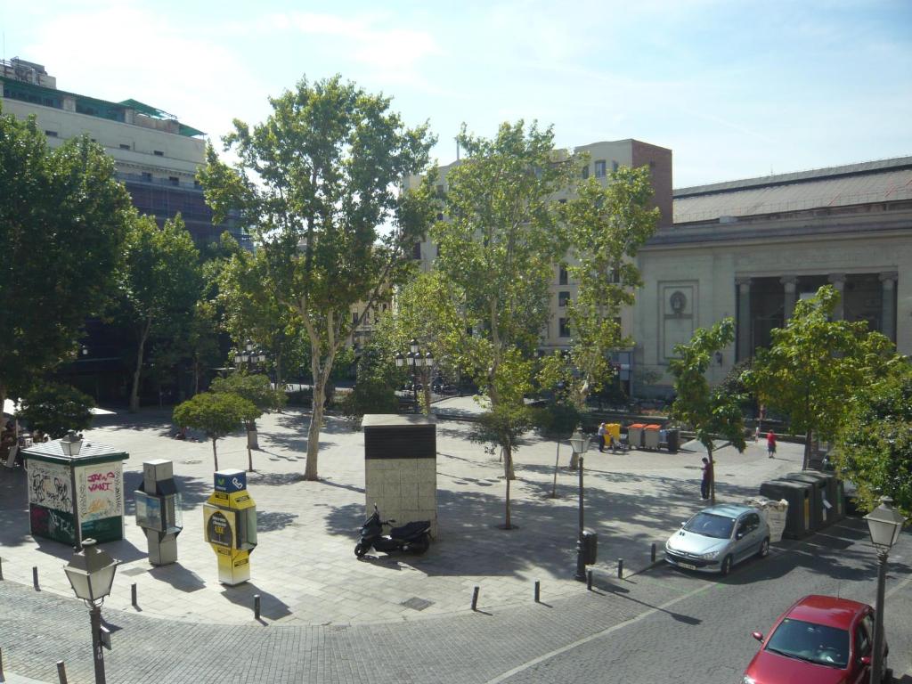 un parking avec des voitures et des arbres dans une ville dans l'établissement Hostal Triana, à Madrid