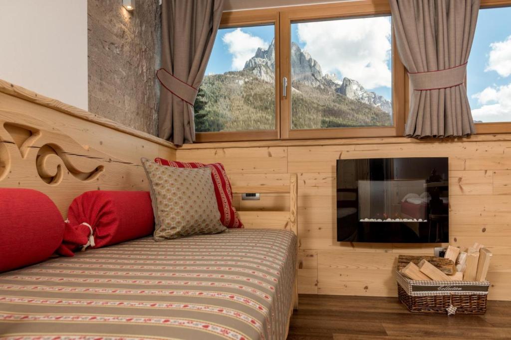 een slaapkamer met een bed, een open haard en een televisie bij Hotel Garni Lastei in Pozza di Fassa