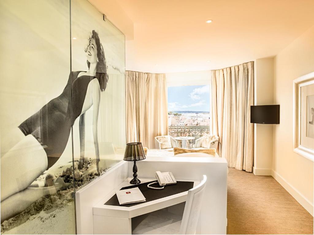 una habitación de hotel con una foto de una mujer en la pared en Hotel Renoir, en Cannes