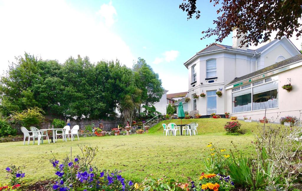 einen Garten mit Stühlen und einem Tisch vor einem Haus in der Unterkunft The Great Western B&B in Paignton