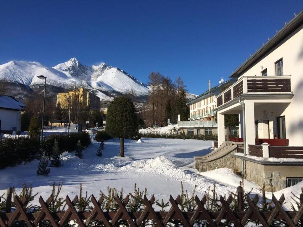 ein Gebäude mit einem schneebedeckten Berg im Hintergrund in der Unterkunft Vila Mala Marta in Tatranská Lomnica