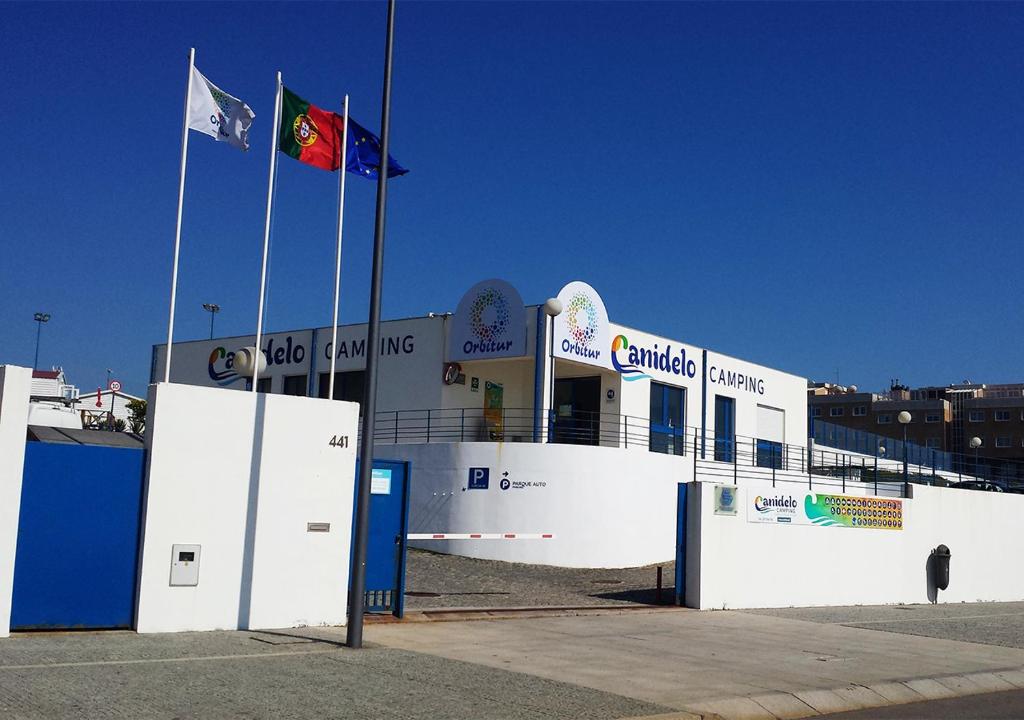 un edificio con dos banderas delante en Parque de Campismo Orbitur Canidelo, en Vila Nova de Gaia