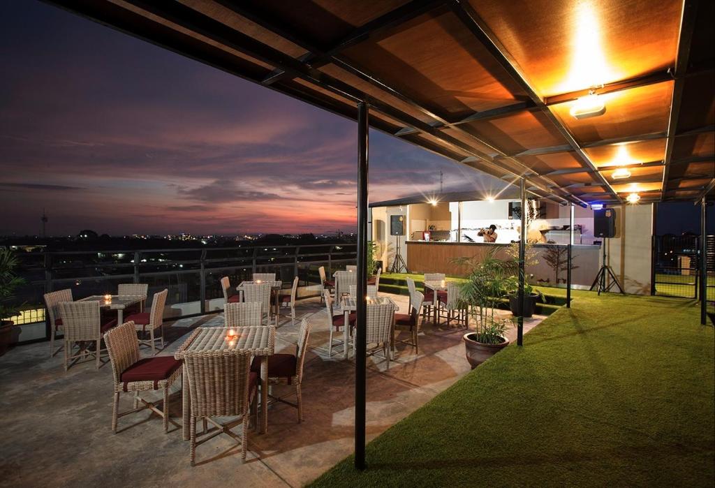 eine Dachterrasse mit Tischen und Stühlen in der Nacht in der Unterkunft Yellow Star Gejayan Hotel in Yogyakarta