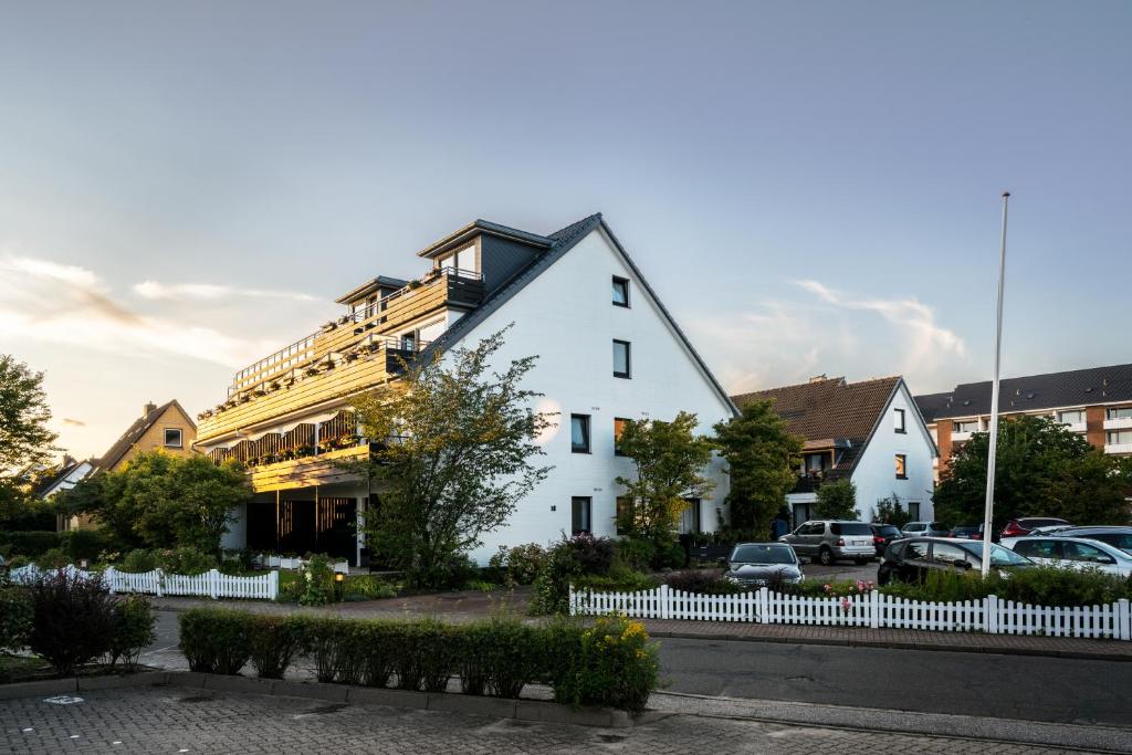 een wit gebouw met een hek ervoor bij Das Frühstückshotel Büsum in Büsum