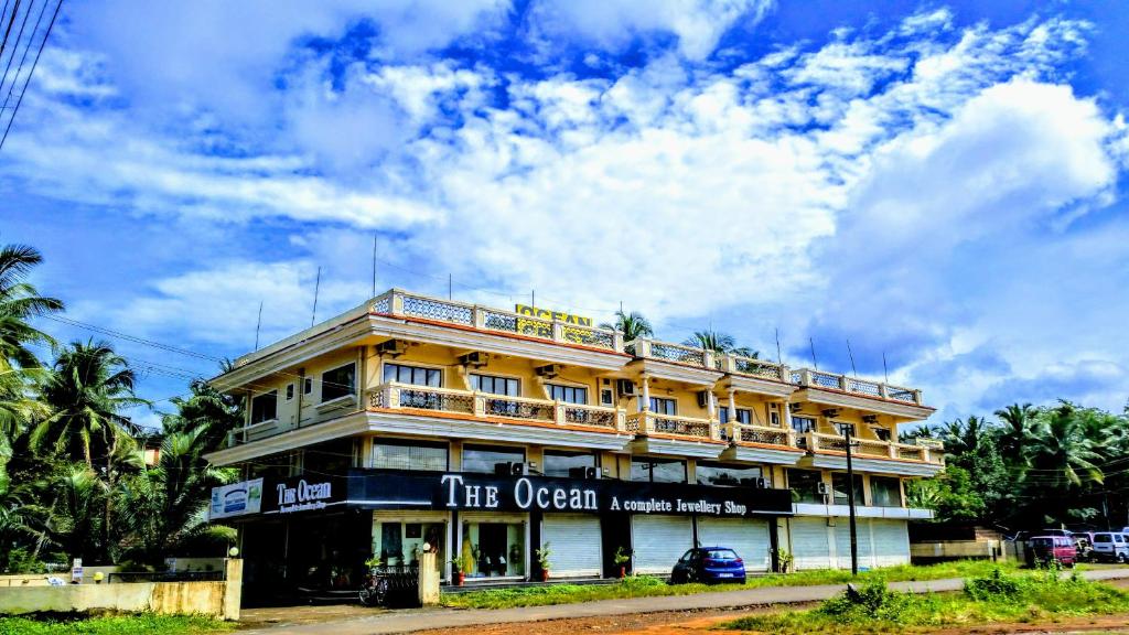 a large yellow building with a sign on it at Ocean Crest Hotel in Colva