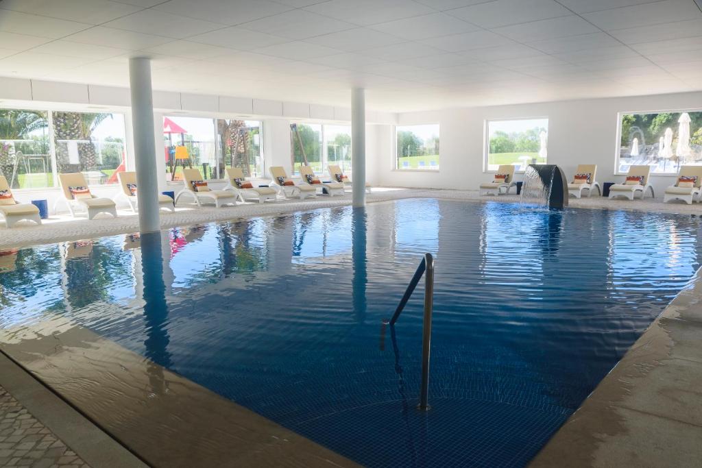 - une grande piscine avec des chaises dans un bâtiment dans l'établissement MH Atlantico, à Peniche