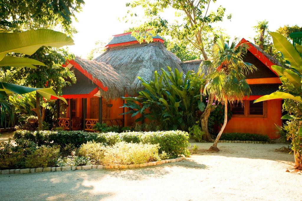 une petite maison avec un toit de chaume dans un jardin dans l'établissement The Caves, à Negril