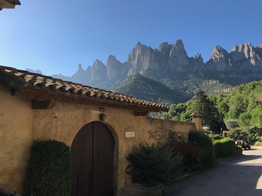 un bâtiment avec une porte et des montagnes en arrière-plan dans l'établissement Montserrat La Calsina, à Monistrol de Montserrat