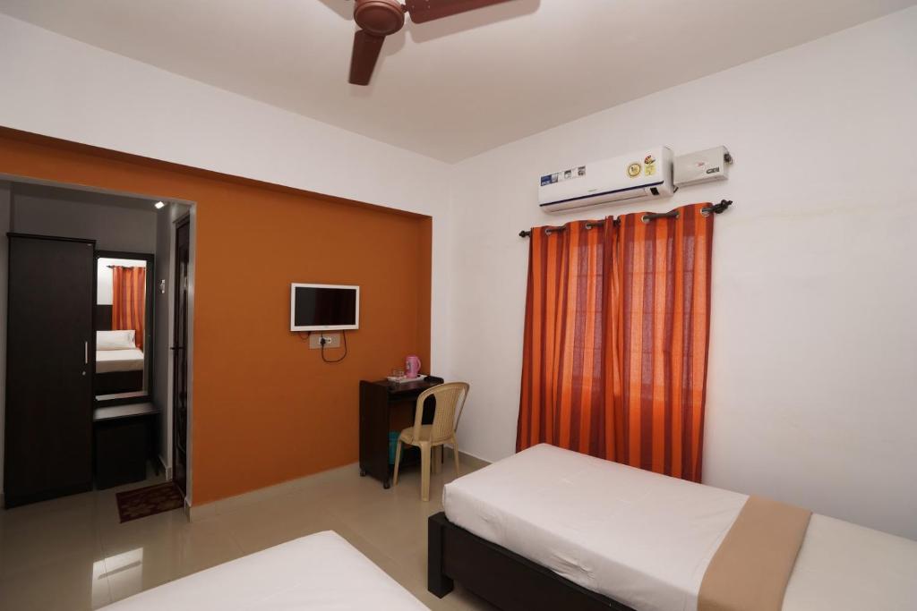 1 dormitorio con 1 cama, escritorio y TV en KV Residency, en Coimbatore