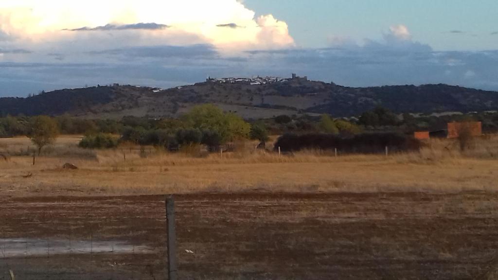 uma cerca num campo com uma montanha ao fundo em Painel de Monsaraz em Reguengos de Monsaraz