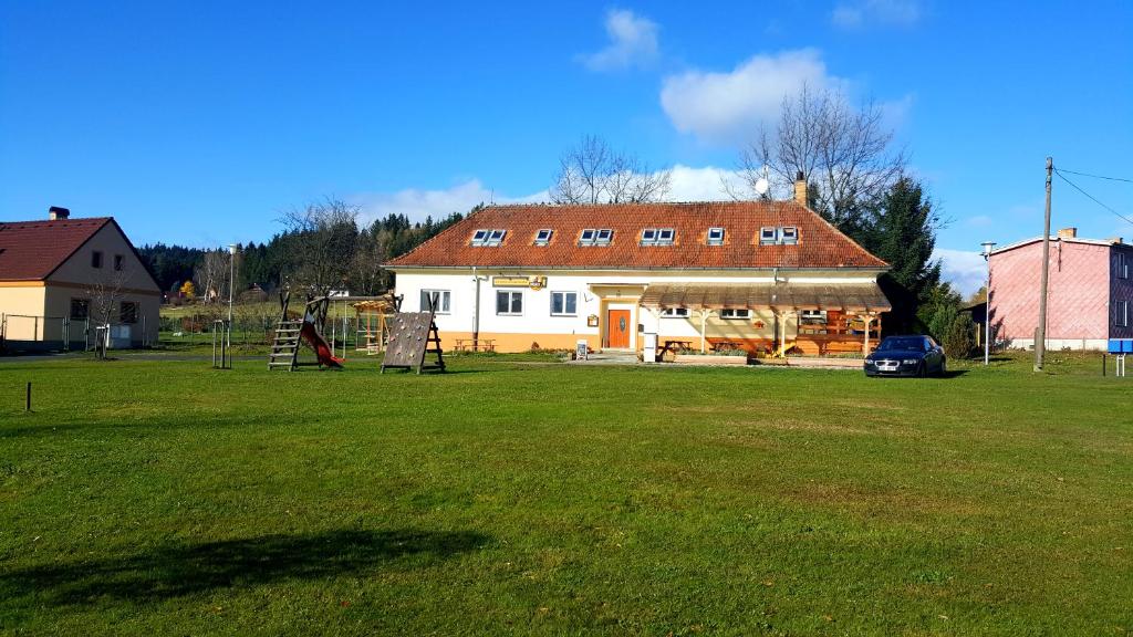 een huis met een tuin met een speeltuin ervoor bij Penzion-Na Navsi in Horní Planá