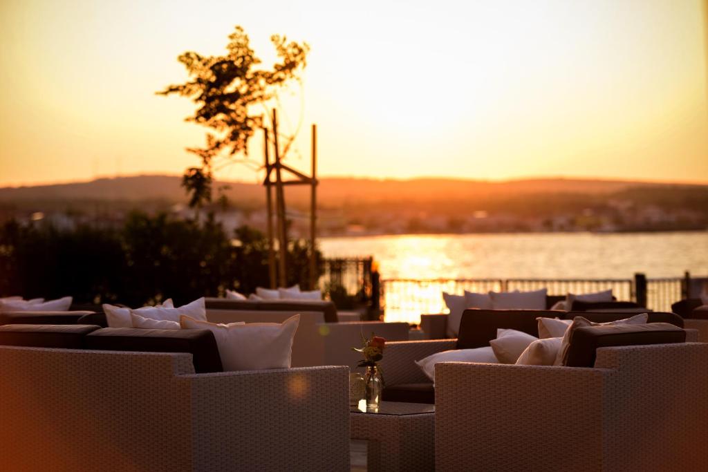 un groupe de chaises blanches au coucher du soleil en arrière-plan dans l'établissement Sunset Deluxe Apartments, à Vir