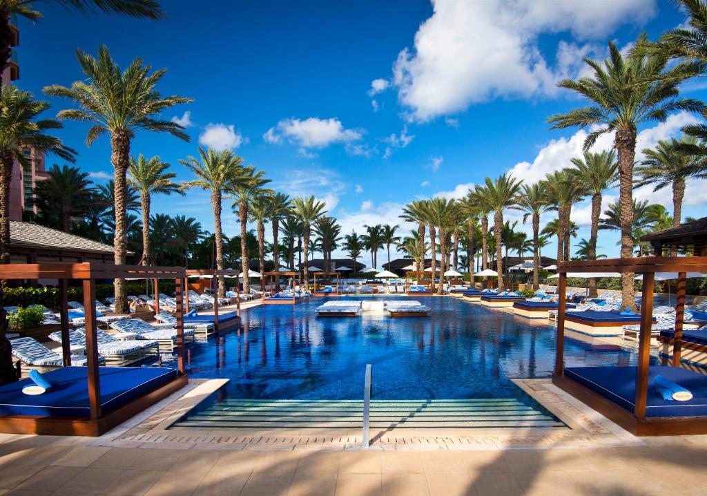 une piscine dans un complexe avec des palmiers et des bateaux dans l'établissement The Cove at Atlantis, à Nassau