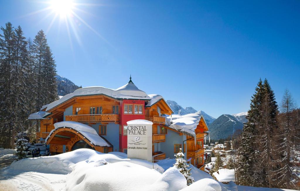 un edificio en la nieve con el sol detrás en Cristal Palace Hotel, en Madonna di Campiglio