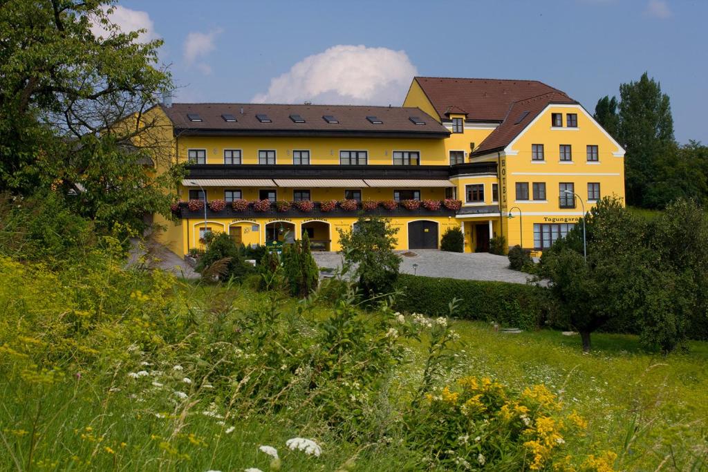 un grand bâtiment jaune au sommet d'une colline dans l'établissement Hotel Stich, à Manhartsbrunn