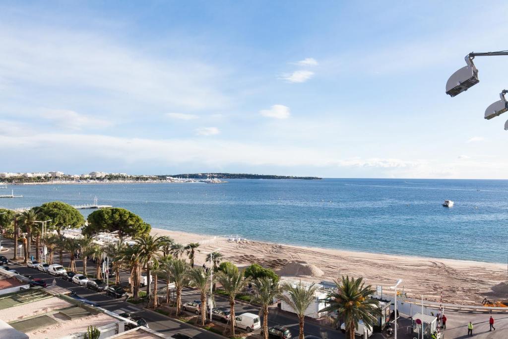 - une vue sur la plage bordée de palmiers et l'océan dans l'établissement Violet, bord de mer, à Cannes