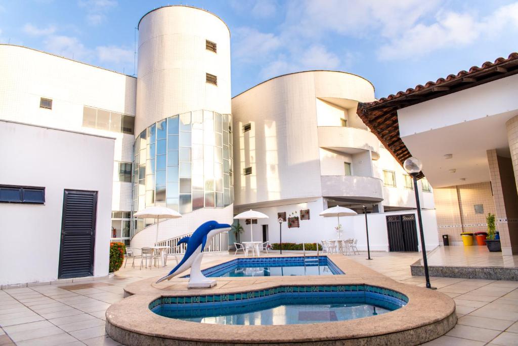 - une piscine dans la cour d'un bâtiment avec une statue de dauphins dans l'établissement Costa Atlantico Hotel, à São Luís