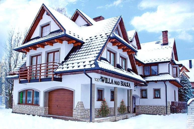 a large white house with snow on top of it at Willa Nad Białką in Białka Tatrzanska