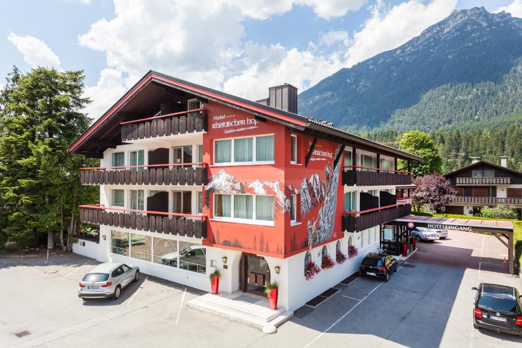 um edifício vermelho com carros estacionados num parque de estacionamento em Hotel Rheinischer Hof em Garmisch-Partenkirchen